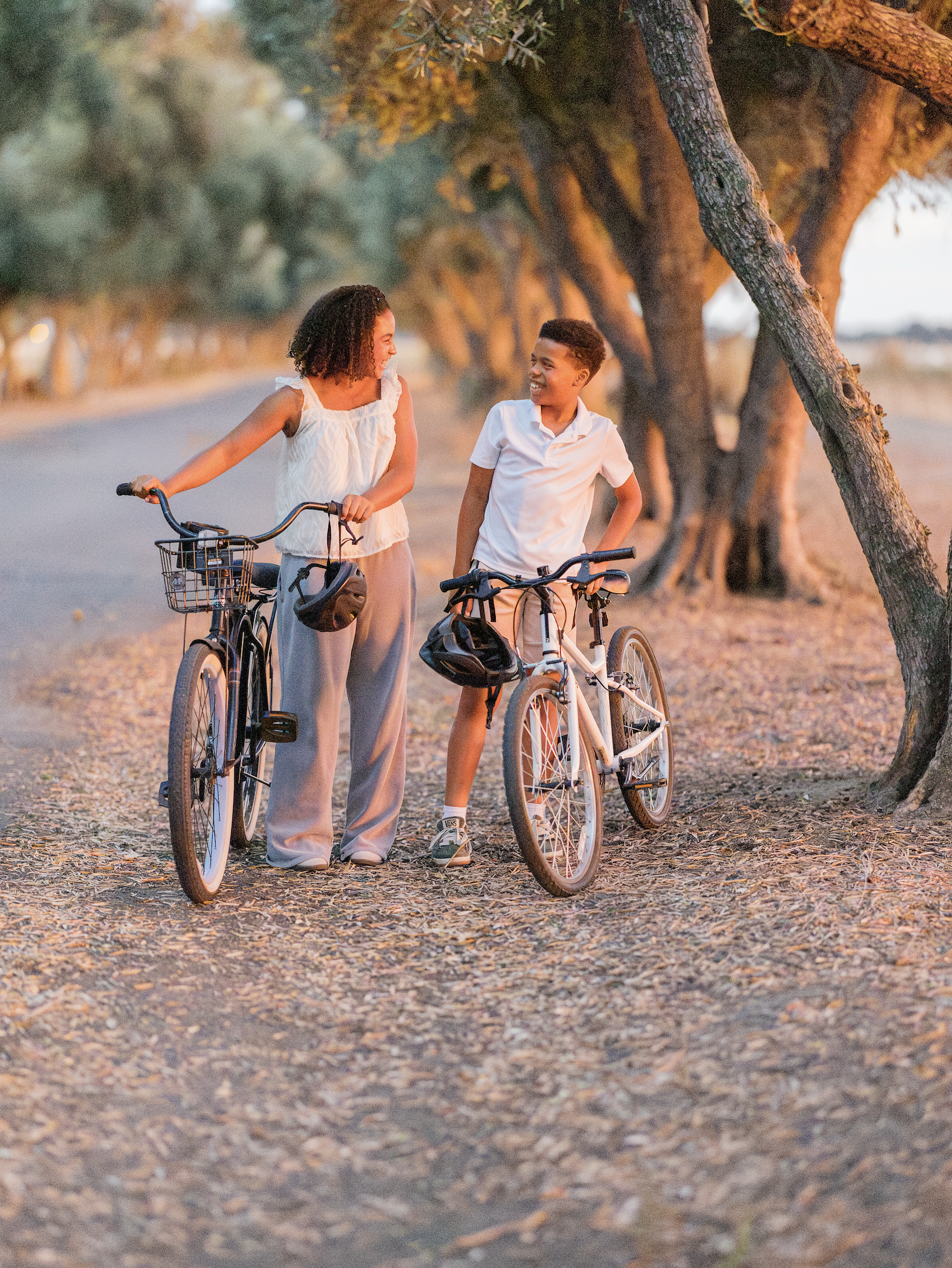 Two teens biking on a tree-lined path at golden hour